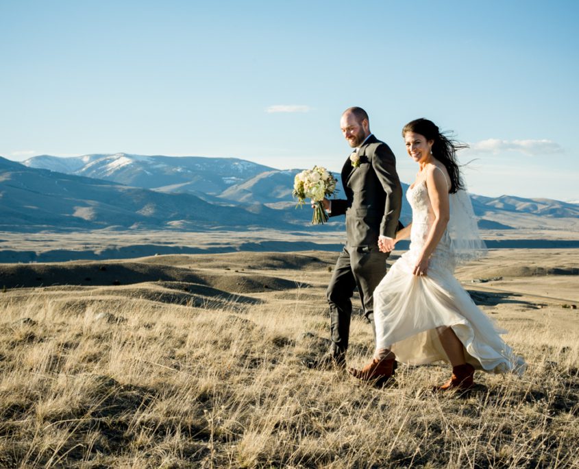 newlyweds-walk-mountain-landscape-at-chico-hot-springs-wedding